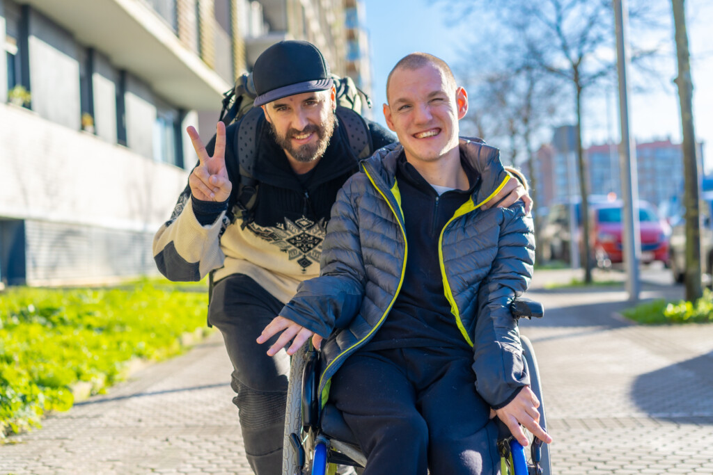 Portrait of a disabled person in a wheelchair with a friend, normality of disabled people man standing next to a friend in a wheelchair
